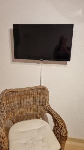 a wicker chair with a television on a wall at La joyeuse étape in Sonceboz