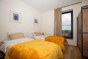 two beds in a room with a window at Modern en gezellig appartement vlak aan het strand in Blankenberge