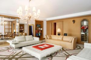 una sala de estar con muebles blancos y una lámpara de araña. en Hôtel Le Royal Monceau Raffles Paris en París