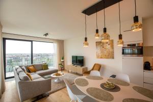 un soggiorno con tavolo e divano di Modern en gezellig appartement vlak aan het strand a Blankenberge