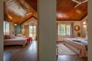 Dos camas en una habitación con techos de madera. en LohonoStays Ivy Cottage, en Dehradun