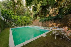 una piscina en un patio con mesa y sillas en LohonoStays Ivy Cottage, en Dehradun