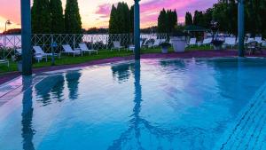 a swimming pool with chairs and a sunset in the background at Naantali Spa Hotel in Naantali