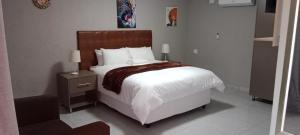 a bedroom with a large white bed with a wooden headboard at CyC Guest Lodge in Giyani