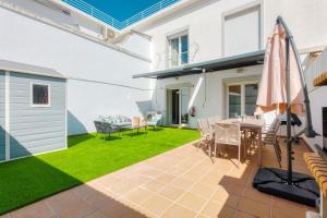 a patio with a table and chairs and a lawn at Stunning House with Terrace in Lisbon
