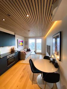a living room with a table and a kitchen at Lovely and exclusive northern lights apartment with excellent view. in Tromsø