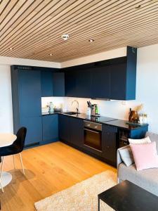 a kitchen with blue cabinets and a table and a couch at Lovely and exclusive northern lights apartment with excellent view. in Tromsø