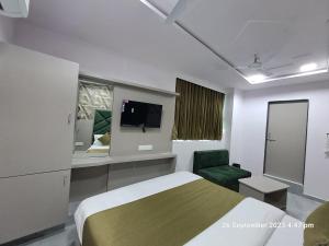 a hotel room with a bed and a green chair at HOTEL KINGDOM in Gandhinagar