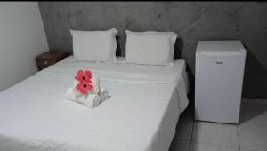 Una cama blanca con una flor en una caja. en Casa Flôr, en Fernando de Noronha