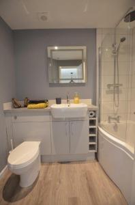 a bathroom with a sink and a toilet and a tub at Elouera, 21 Isis Lake in South Cerney