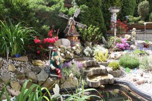 a miniature garden with a windmill and a pond at Villa Anastazis - Penzion Eden in Karlovy Vary