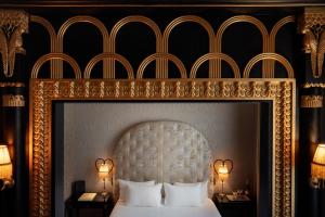 a bedroom with a white bed with a gold frame at Maison Souquet, Hotel & Spa in Paris