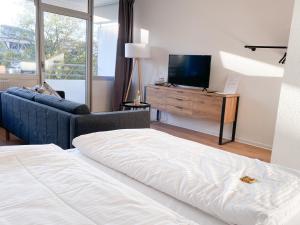 ein Schlafzimmer mit einem Bett, einem TV und einem Sofa in der Unterkunft Central Apartment Rhein Neuss-Düsseldorf Messe in Neuss