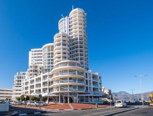 ein hohes weißes Apartmenthaus mit davor geparkt in der Unterkunft Hibernian Towers 309 Strand - Luxury Self Catering in Kapstadt