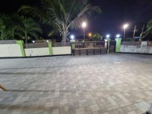 a parking lot with a fence and palm trees at night at Natako Apartment in Apenkwa