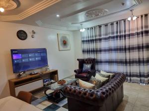 a living room with a leather couch and a tv at Natako Apartment in Apenkwa