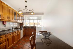 a kitchen with wooden cabinets and a chandelier at Live Vagueira Beach in Praia da Vagueira