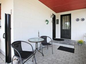 een patio met 3 stoelen en een tafel op een veranda bij 8 person holiday home in Struer in Humlum