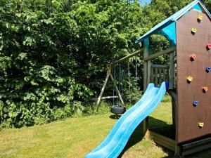 a playground with a blue slide next to a building at 8 person holiday home in Struer in Humlum