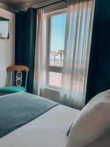 1 dormitorio con ventana, cama y silla en Hotel Puerto Chinchorro en Arica