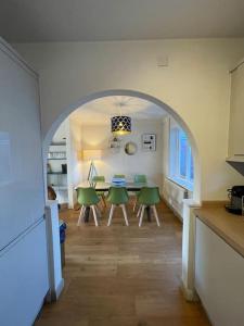a kitchen and dining room with a table and green chairs at Charming North Norfolk flint cottage in Baconsthorpe