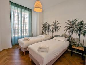 2 łóżka w pokoju z palmami na ścianie w obiekcie Happyfew Palazzo del sol w Nicei