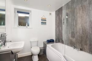 een badkamer met een bad, een toilet en een wastafel bij Church House Barn Lake District & Solway Coast with Solway Firth views in Silloth