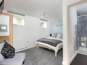 een slaapkamer met een bed, een bank en ramen bij Church House Barn Lake District & Solway Coast with Solway Firth views in Silloth