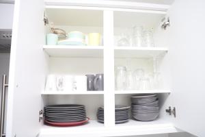 a white cabinet filled with plates and dishes at Superb 3 Bedroom flat in Stafford in Stafford