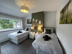 1 dormitorio con 2 camas y ventana en Modern 3-bed stay-away-home sleeps 6 nr Manchester, en Mánchester