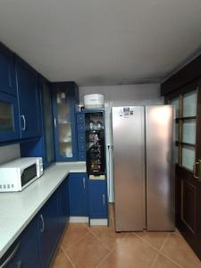 een keuken met een roestvrijstalen koelkast en blauwe kasten bij Chalet Adosado en Rincón in Rincón de la Victoria