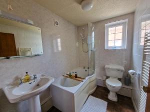 a bathroom with a tub and a sink and a toilet at Windale, Highcroft & Garth @ Wetheral Cottages in Great Salkeld +32 photos