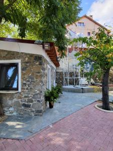 a stone house with a tree next to a building at Kallithea INN in Platres