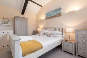 a bedroom with a white bed with a yellow blanket at Cornflower in Saundersfoot