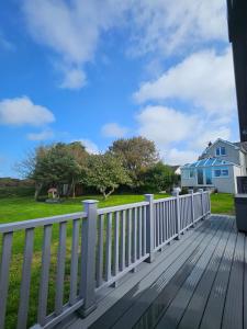 a white fence on a wooden deck with a yard at Four Winds B&B StDavids in St. Davids