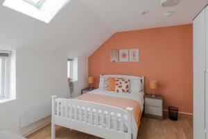 um quarto com uma cama branca e uma parede laranja em Wonderland - Fitzrovia - by Frankie Says em Londres