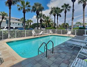 a swimming pool with chairs and palm trees at Casa Mar Y Palmera 202a in Clearwater Beach