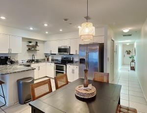 una cocina con armarios blancos y una mesa con sillas. en Casa Mar Y Palmera 202a en Clearwater Beach