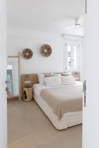 a white bedroom with a large bed and a mirror at KAMEO, Antiparos in Antiparos