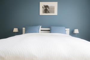 a bedroom with a white bed with blue walls at Two White Pigeons in Ieper