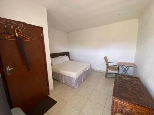 um pequeno quarto com uma cama e uma mesa em Aeropark Residencial(1) em Maputo