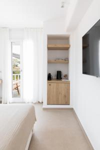 a white bedroom with a bed and a tv at KAMEO, Antiparos in Antiparos