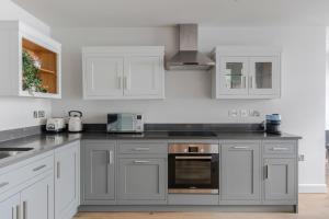 a kitchen with gray and white cabinets and appliances at London's Calling - Farringdon - by Frankie Says in London