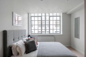 a bedroom with a bed with pillows and a window at London's Calling - Farringdon - by Frankie Says in London