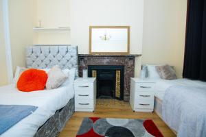 uma sala de estar com 2 camas e uma lareira em Victorian Woods BnB em Londres