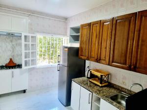 - une cuisine avec des placards en bois et un réfrigérateur dans l'établissement Green Family House 3 Bedrooms with Garden View Casablanca, à Casablanca
