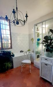 y baño con bañera, silla y lámpara de araña. en Maison d'Hôtes Archangels Home, en Saint-Saëns