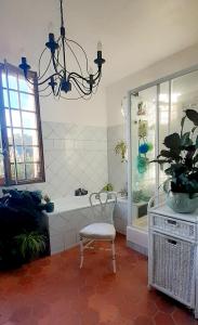 a bathroom with a tub and a chair and a chandelier at Maison d'Hôtes Archangels Home in Saint-Saëns