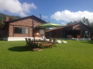 uma mesa e cadeiras com um guarda-sol em frente a uma casa em Villa Santa Maria em Santa María del Oro