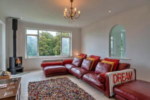 Finest Retreats - The View في شالدون: غرفة معيشة مع أريكة جلدية حمراء ومدفأة